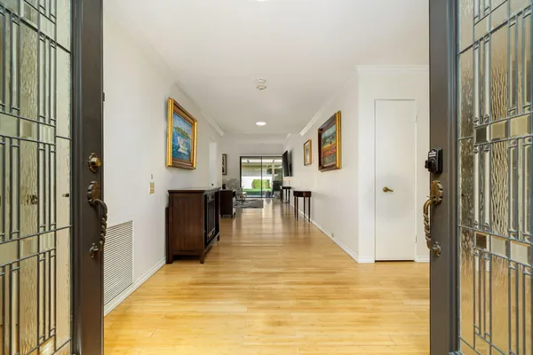 a view of a hallway with wooden floor and a living room