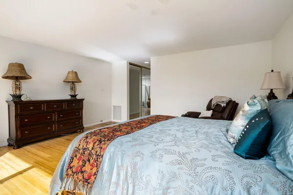a bedroom with a bed and a lamp on dresser