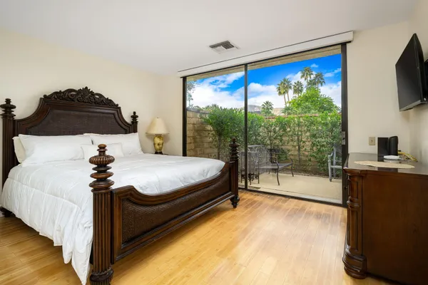 a bedroom with a large bed and a flat tv screen on dresser