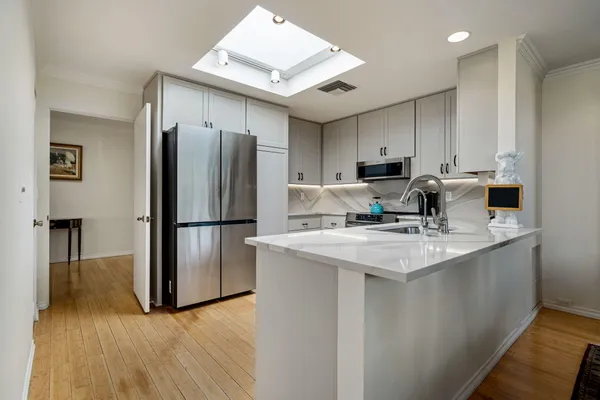 a kitchen with stainless steel appliances granite countertop a refrigerator a sink a stove and a refrigerator with wooden floor