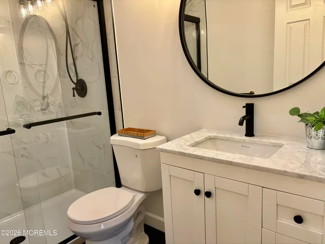 a bathroom with a granite countertop toilet sink and mirror