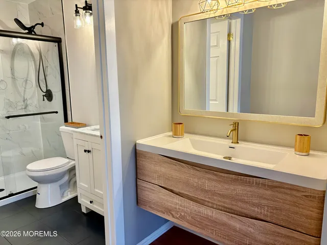 a bathroom with a granite countertop toilet sink and mirror