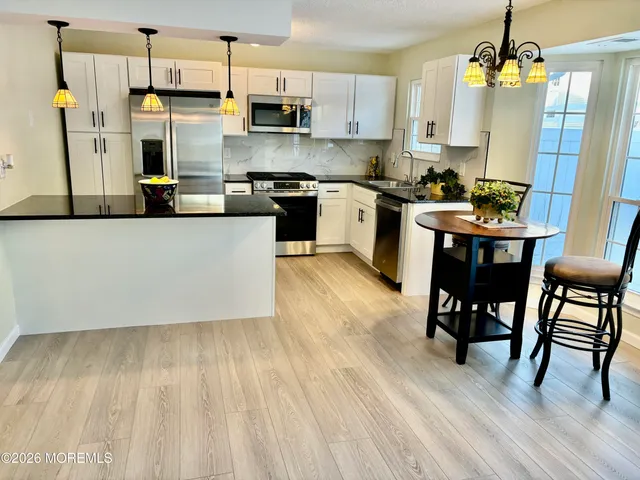 a kitchen with stainless steel appliances a refrigerator a stove a sink dishwasher and a dining table with wooden floor