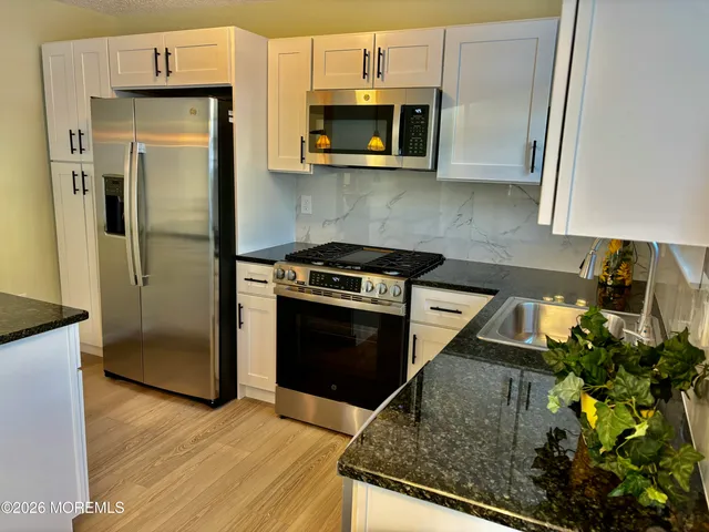 a kitchen with granite countertop a stove a microwave a sink and a refrigerator