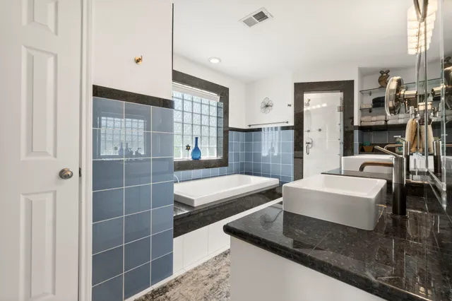 a bathroom with a granite countertop tub a sink and a shower