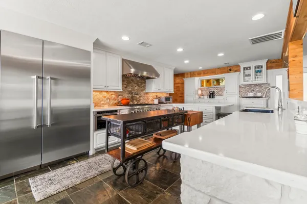 a kitchen with stainless steel appliances kitchen island granite countertop dining table chair and a refrigerator