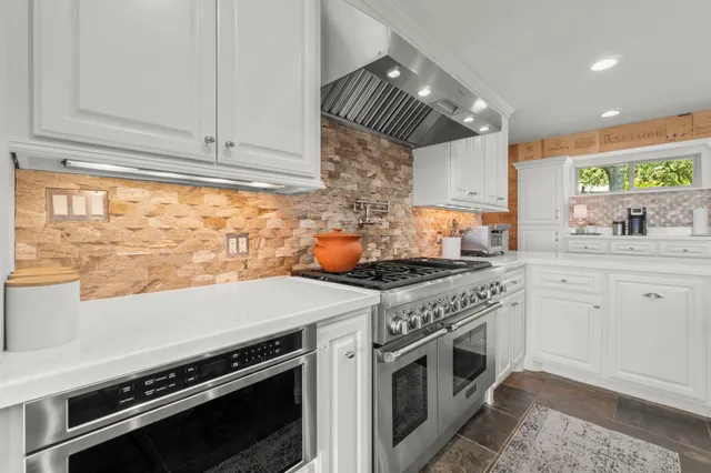 a kitchen with stainless steel appliances a stove a sink and white cabinets