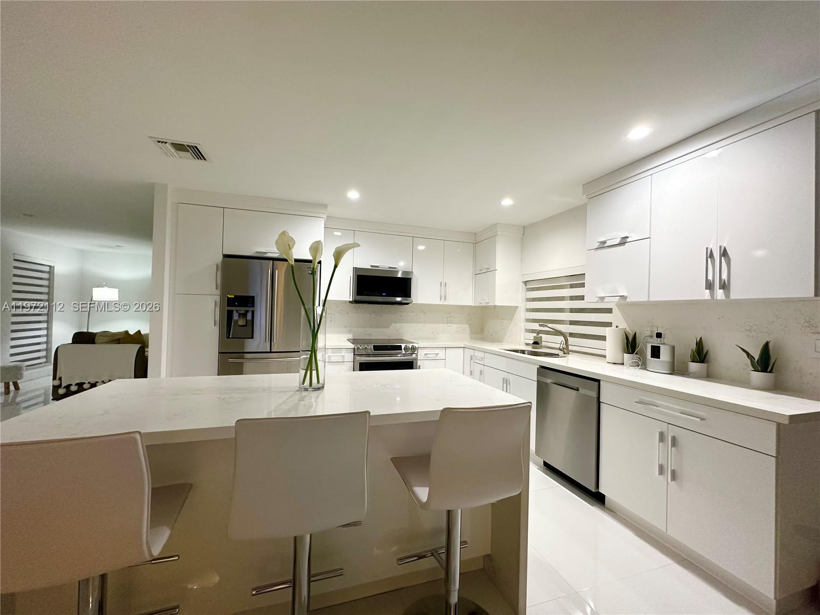 9230 Southwest 68th Street Miami, FL 33173 - Photo 11 of 29 a kitchen with stainless steel appliances kitchen island granite countertop a sink and cabinets