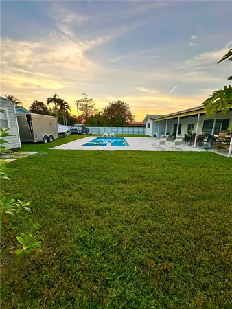 a view of a house with a big yard and large trees