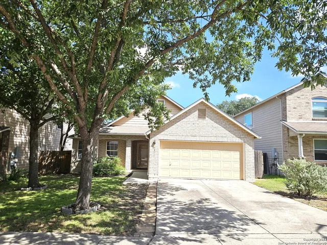 a front view of a house with a garden and trees