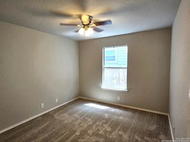 an empty room with windows and chandelier fan