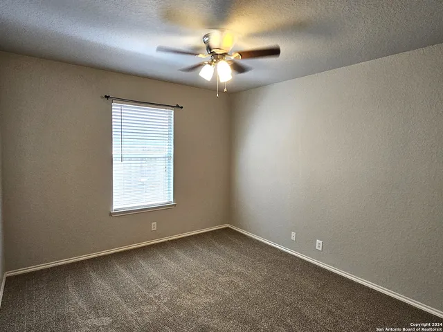 an empty room with a window and a ceiling fan