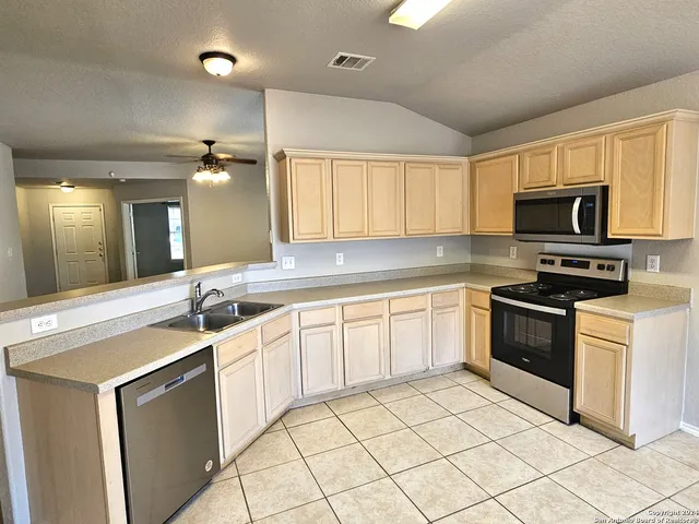 a kitchen with granite countertop a sink stainless steel appliances and cabinets