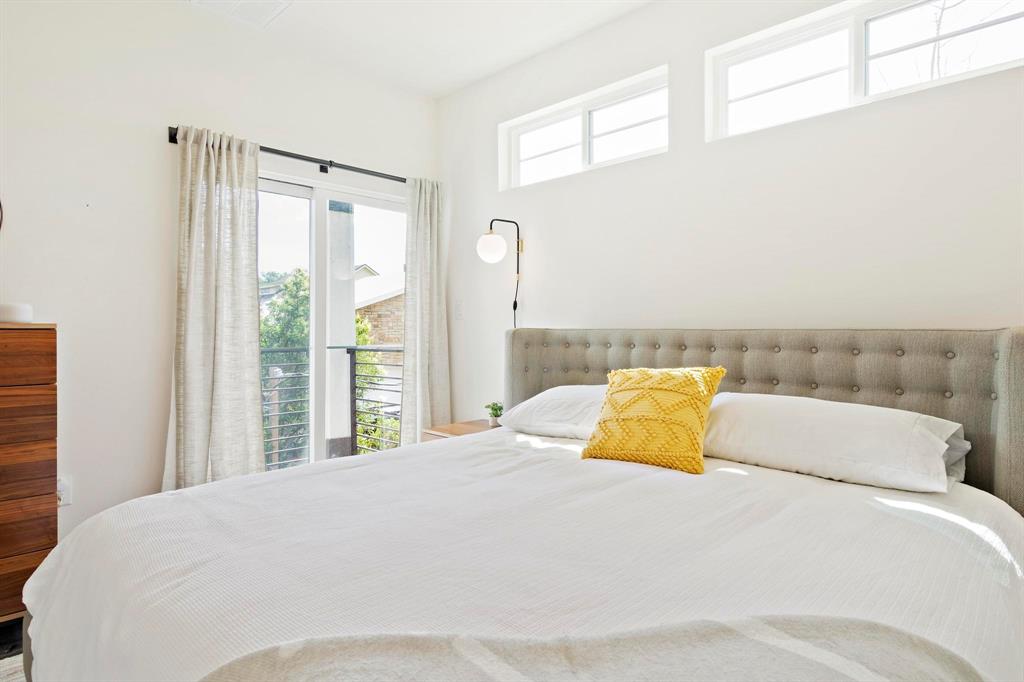 911 Stobaugh Street, Unit 2 Austin, TX 78757 - Photo 15 of 26 Bright bedroom featuring a built-in wall sconce, high windows, and a sliding glass door leading to a balcony with metal railings