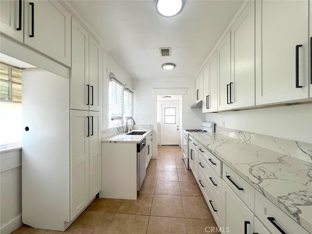 1554 East Woodbury Road Pasadena, CA 91104 - Photo 7 of 13 a kitchen with granite countertop a sink a stove refrigerator and cabinets