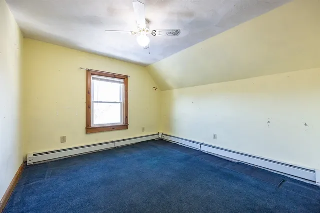 an empty room with a chandelier fan and windows
