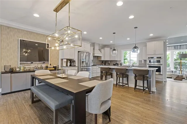 a kitchen with stainless steel appliances granite countertop table chairs sink refrigerator and microwave