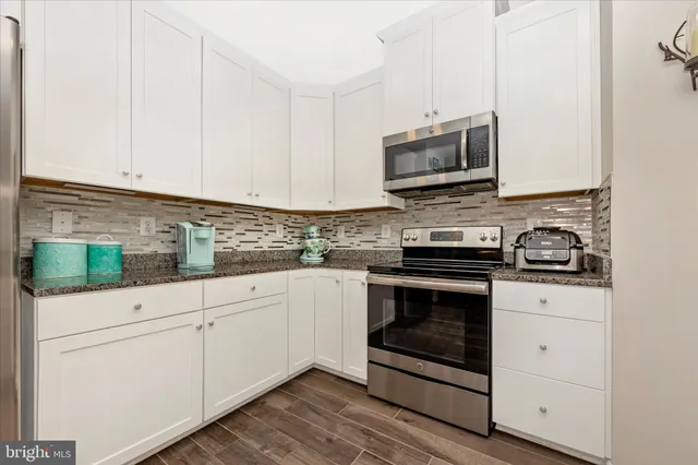 a kitchen with granite countertop white cabinets stainless steel appliances and sink