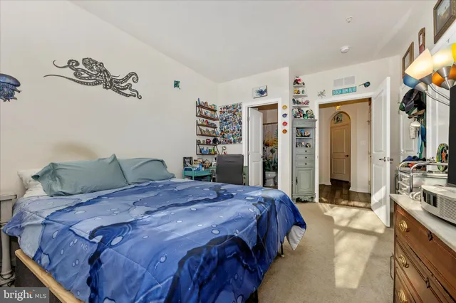 a bedroom with a large bed a flat tv screen and dresser