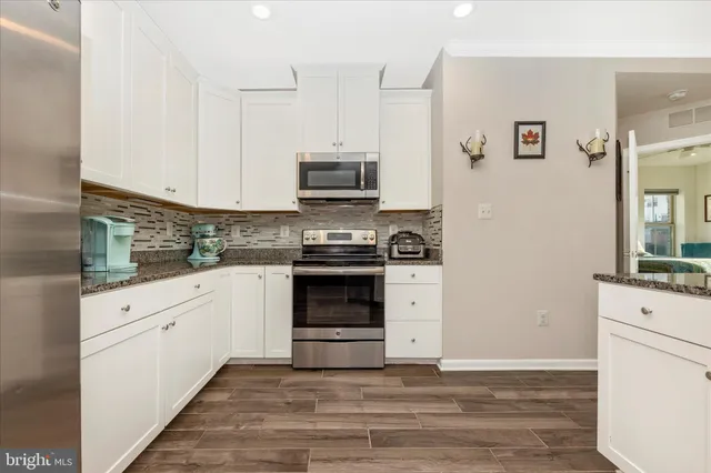 a kitchen with stainless steel appliances white cabinets and a stove top oven