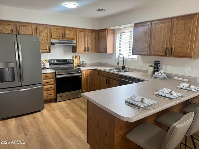 a kitchen with a sink a stove a refrigerator and wooden cabinets