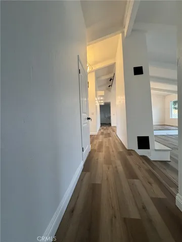 a view of a hallway with wooden floor and a bathroom
