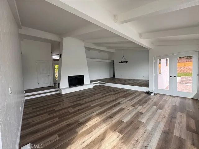 a view of empty room with wooden floor and fireplace