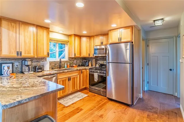 a kitchen with stainless steel appliances granite countertop a refrigerator a stove and a sink
