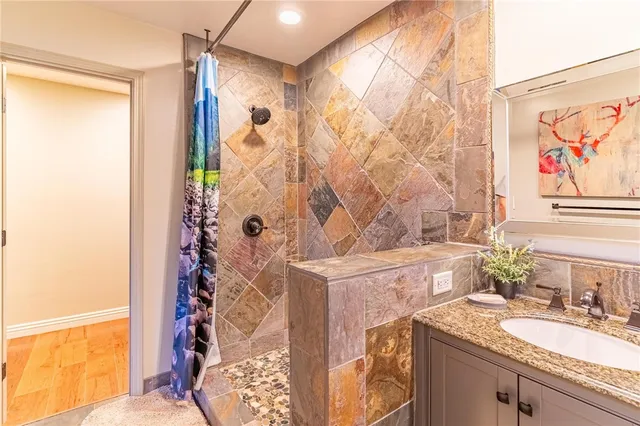 a bathroom with a granite countertop sink a mirror and a shower