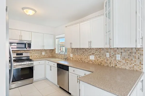 a white kitchen with granite countertop stainless steel appliances