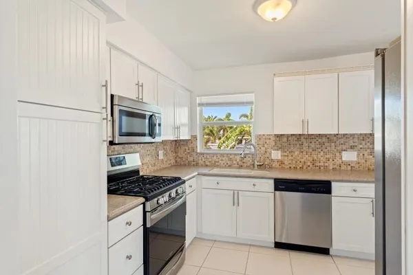 a kitchen with white cabinets appliances and a window