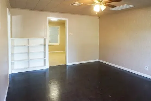 an empty room with wooden floor and fan
