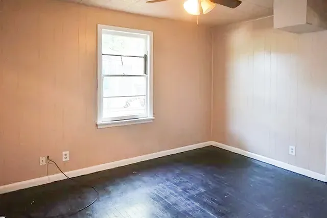 an empty room with wooden floor and windows