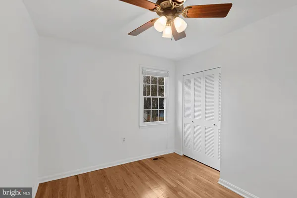 an empty room with wooden floor fan and windows
