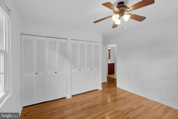 an empty room with wooden floor chandelier fan and closet