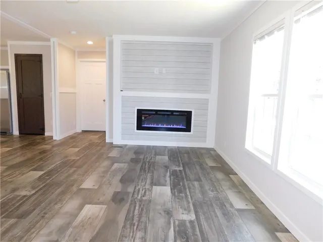 an empty room with wooden floor fireplace and windows