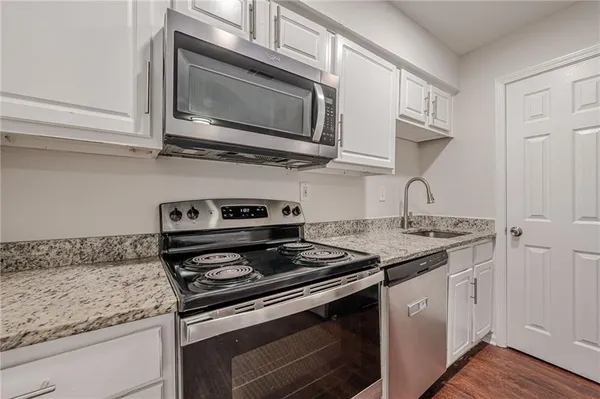 a kitchen with stainless steel appliances granite countertop white cabinets and stove
