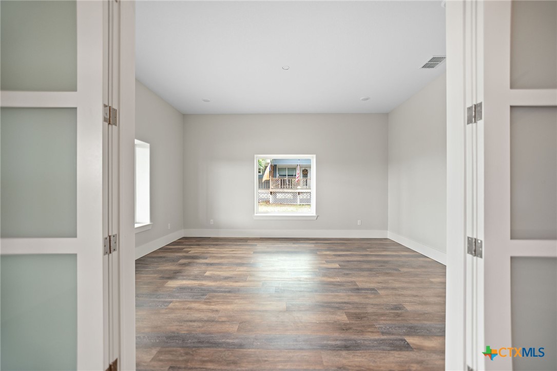 2062 Harrison Avenue Port O'Connor, TX 77982 - Photo 10 of 48 a view of an empty room with wooden floor and a window