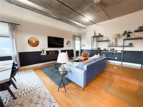 a living room with furniture kitchen view and a wooden floor