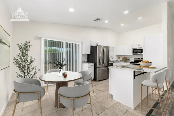a kitchen with stainless steel appliances a dining table chairs and refrigerator