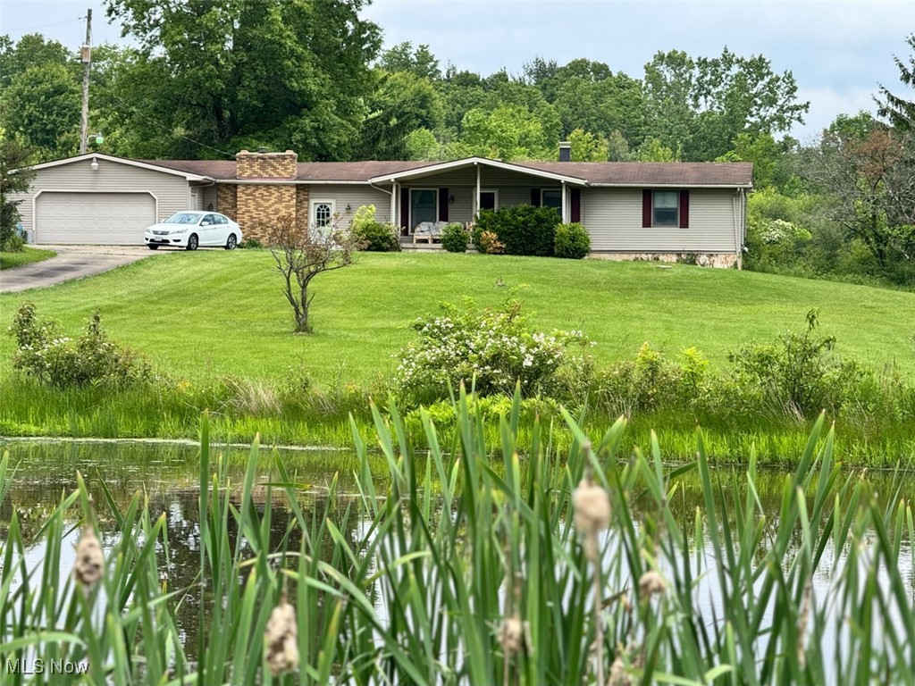 Ranch-style house featuring a front yard, concrete driveway, a garage, and a chimney