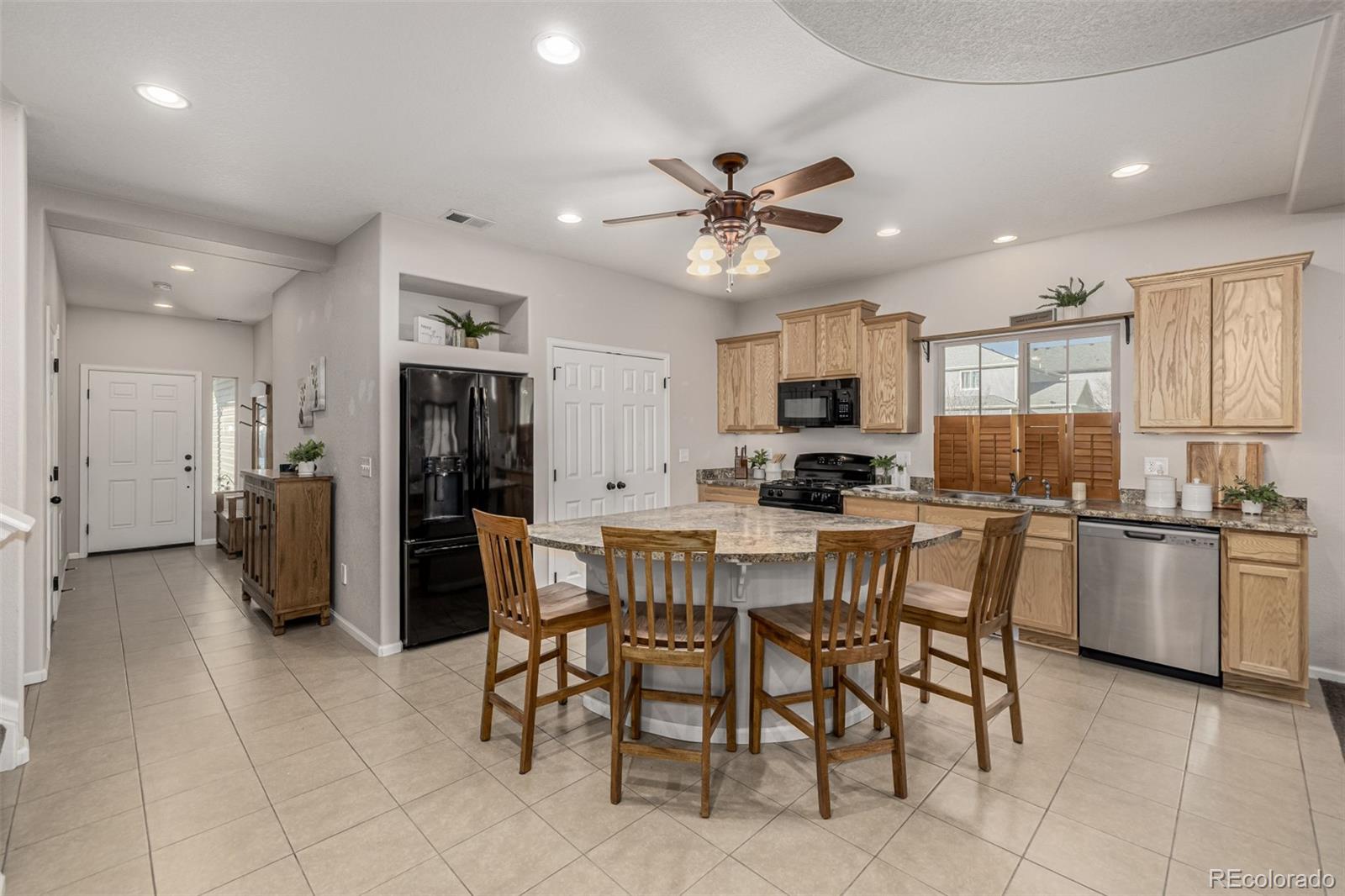 5568 Ceylon Street Denver, CO 80249 - Photo 11 of 43 a kitchen with stainless steel appliances a refrigerator a stove a sink a dining table and chairs
