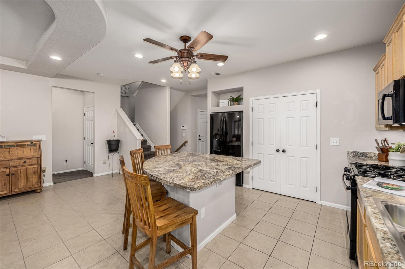 5568 Ceylon Street Denver, CO 80249 - Photo 14 of 43 a kitchen with stainless steel appliances kitchen island granite countertop a table and chairs in it