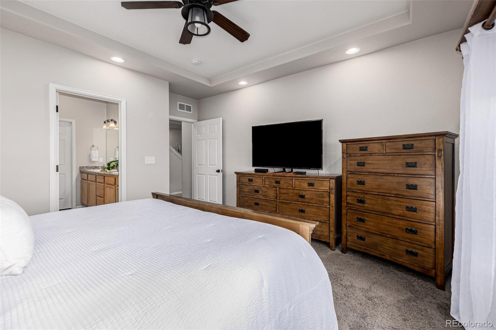 5568 Ceylon Street Denver, CO 80249 - Photo 18 of 43 a bedroom with a bed and a flat screen tv