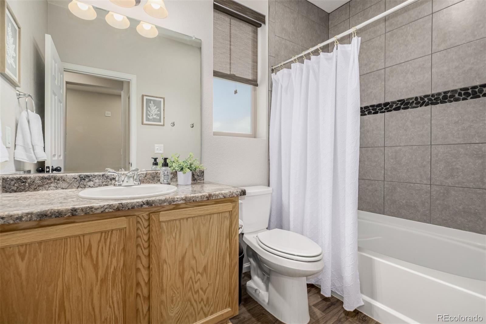 5568 Ceylon Street Denver, CO 80249 - Photo 23 of 43 a bathroom with a granite countertop sink toilet and shower