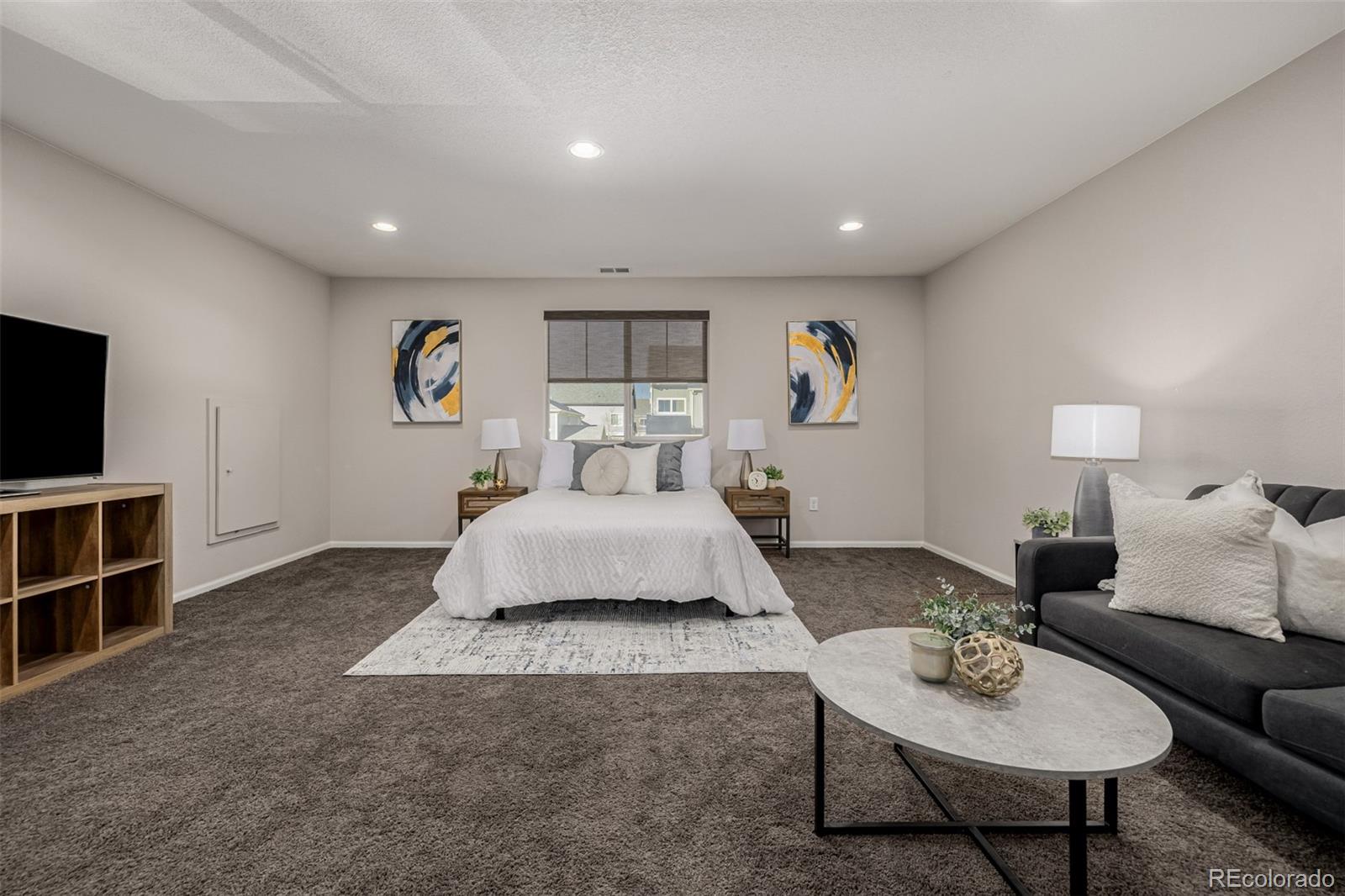 5568 Ceylon Street Denver, CO 80249 - Photo 28 of 43 a spacious bedroom with a bed a couch and a bookshelf with wooden floor