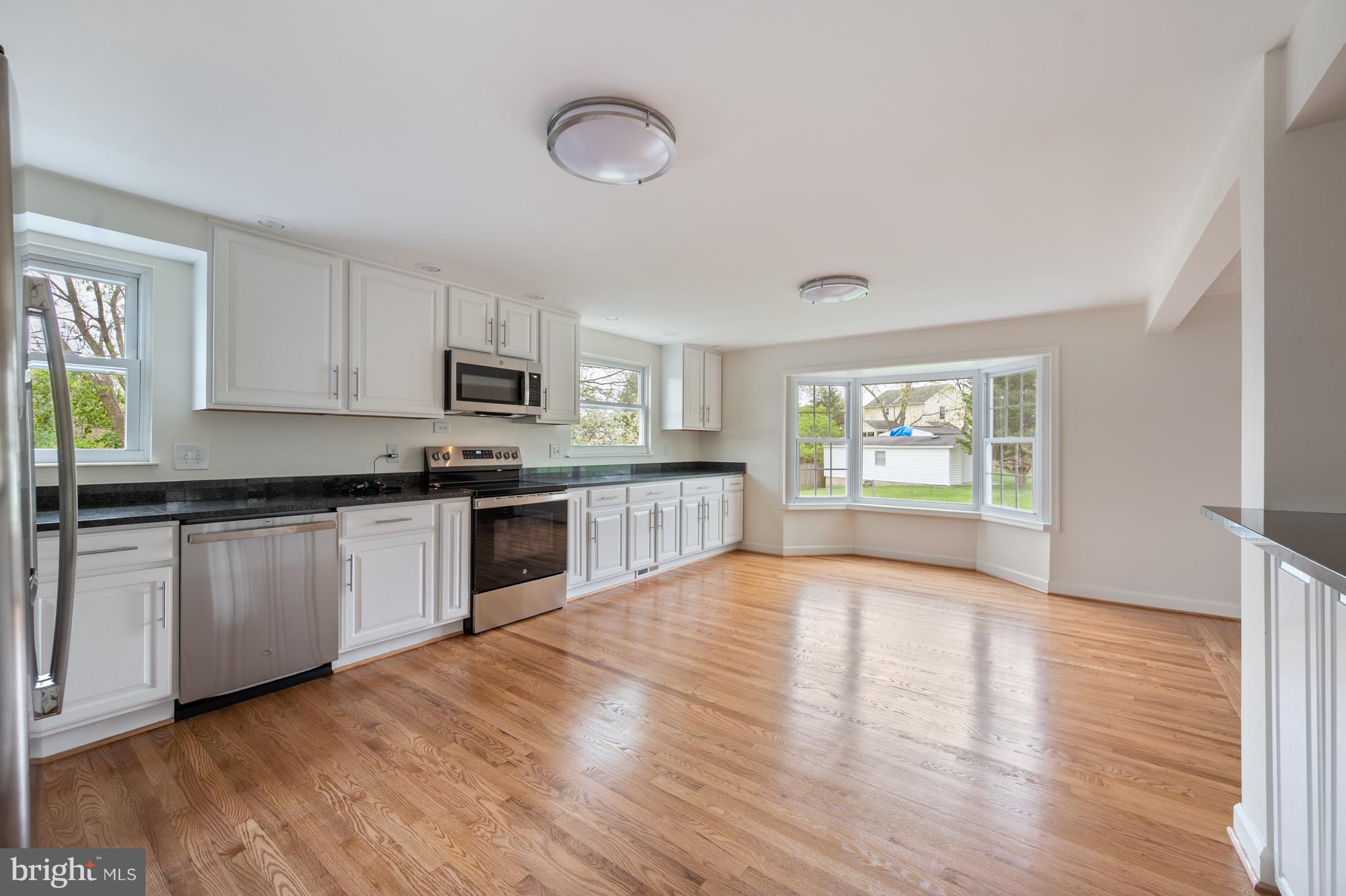 4417 Cub Run Road Chantilly, VA 20151 - Photo 12 of 57 a large kitchen with granite countertop a stove top oven a sink dishwasher and a refrigerator with wooden floor