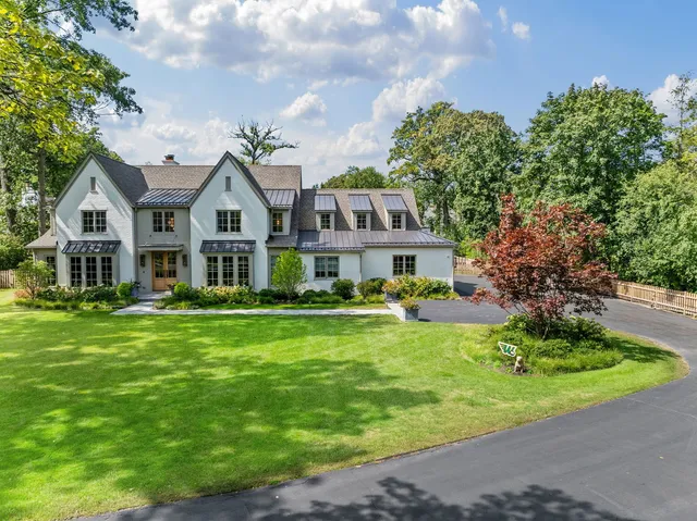 a front view of a house with garden and trees