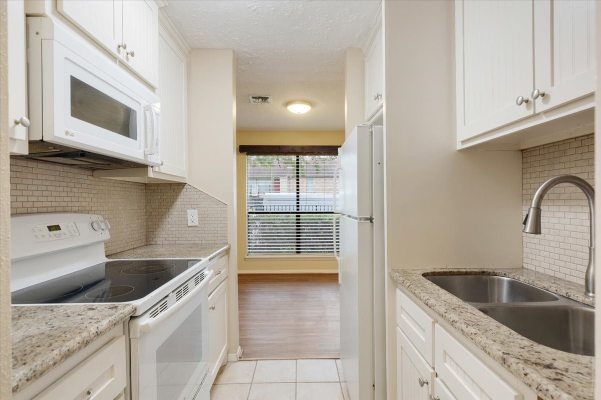 3502 Ocee Street, Unit 3502 Houston, TX 77063 - Photo 6 of 28 This kitchen features modern appliances, granite countertops, and ample cabinetry. It opens to a bright dining area with large windows, providing a cozy and functional space.