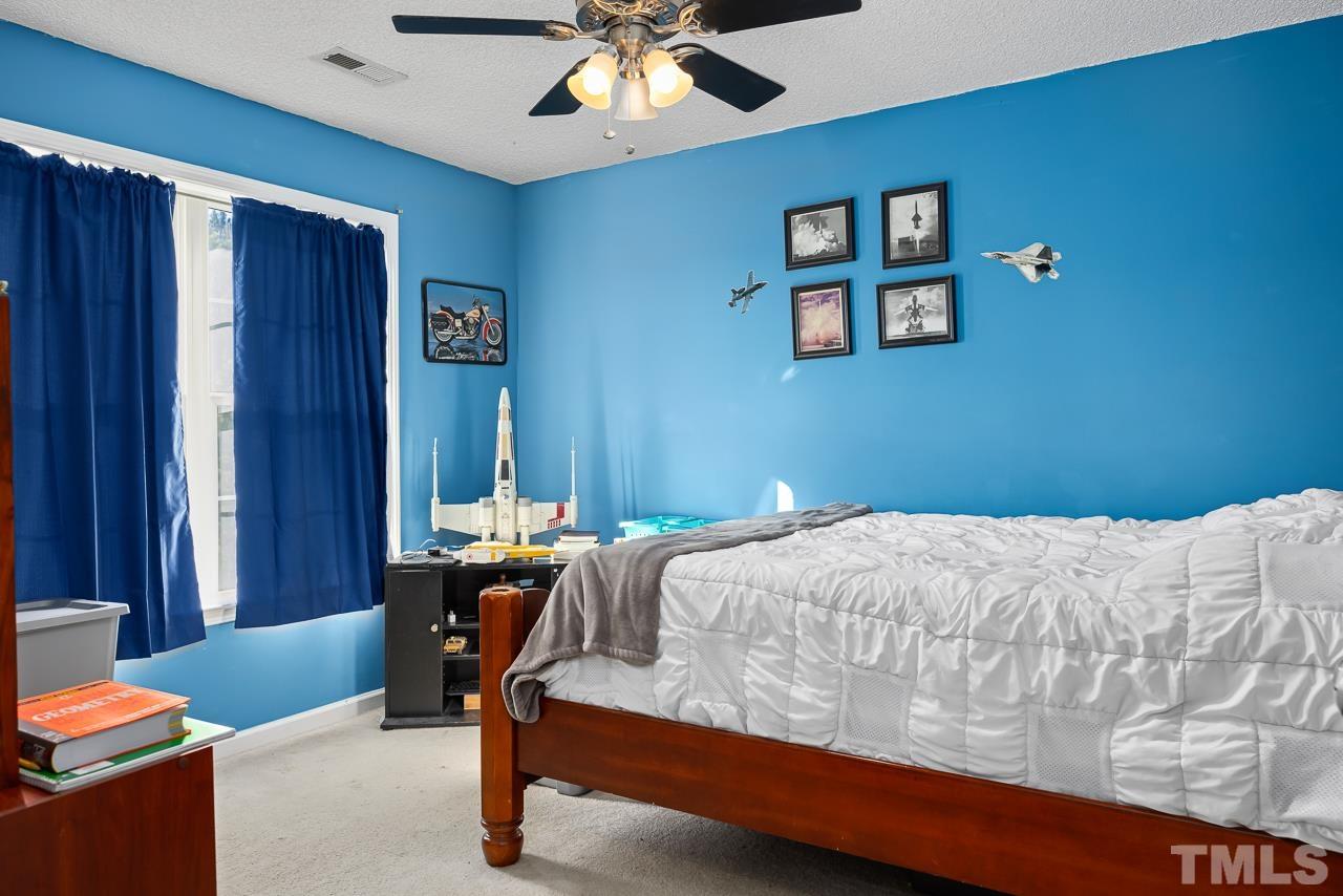 229 Roping Horn Way Willow Spring, NC 27592 - Photo 18 of 30 a bedroom with a bed and a chandelier